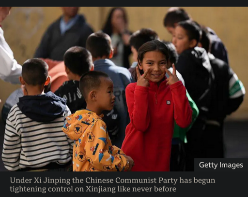 A child turns and gives two peace signs to a photographer, Xinjiang, PRC